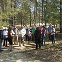 Walk Leader Henri Goulet talks with a Jane's Walk group about the environment in a forested area alongside the Pinhey Dunes..