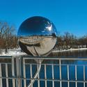 One of two polished spheres making up the installation piece "A View from Two Sides" by Kenneth Emig.   The spheres  mirror the environment in unexpected ways through a panoramic view of sky, river, shores, bridge, pedestrians and cyclists. 
