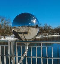 One of two polished spheres making up the installation piece "A View from Two Sides" by Kenneth Emig.   The spheres  mirror the environment in unexpected ways through a panoramic view of sky, river, shores, bridge, pedestrians and cyclists. 